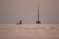 Sunset sailboat and young surfer