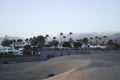 Sunset in the sand dunes of the Maspalomas, palm trees and an oasis in the background. Royalty Free Stock Photo