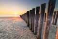 sunset on sand sea beach with wooden poles Royalty Free Stock Photo