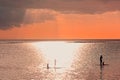 Sunset scene on coming thunderstorm background. Family silhouettes at sunset on ocean.A father with three children are paddling on