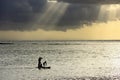 Sunset scene on coming thunderstorm background. A father with three children are paddling on two boards