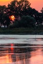 Sunset scene over lake, with sun coming down behind some trees and reflecting on water Royalty Free Stock Photo