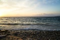 Sunset scenic copyspace wavy seaview and rock beach with beautiful shades of yellow and blue sky background Royalty Free Stock Photo