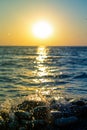 Sunset on the sea: beautiful sky, setting sun, water spray from the waves breaking on the coastal rocks Royalty Free Stock Photo