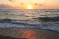 Sunset on the sea coast. The sun is reflected in the wet sand.