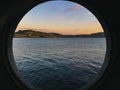 Sunset in the sea. The end of a beautiful day photographed through the porthole of the ship