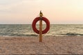 Sunset on the sea and the orange lifebuoy on the beach Royalty Free Stock Photo