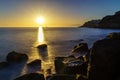 sunset in the sea with the sun on the horizon reflecting the light in the water and on the rocks on the shore. Gran Canaria. Long