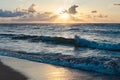 Sunset at the sea. Turquoise water in the ocean in the evening. Yellow sky with small clouds and blue waves at sandy beach at the Royalty Free Stock Photo