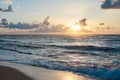 Sunset at the sea. Turquoise water in the ocean in the evening. Yellow sky with small clouds and blue waves at sandy beach at the Royalty Free Stock Photo