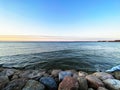 Sunset at sea water green wave splash and seafront stones with pink blue colorful sunset panorama Royalty Free Stock Photo