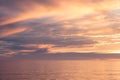 Sunset seascape, orange, blue, yellow, magenta, gold sky reflected in the sea pacific ocean, background photo of sun setting over