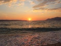 Sunset on the seashore, the setting sun is reflected on the wet sand and on the surface of the water