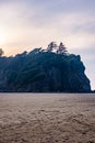 soft sunset behind forested sea stack and sand Royalty Free Stock Photo