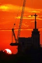 Sunset silhouette construction building tower crane cross on the roof of the church of the Sloane Royalty Free Stock Photo