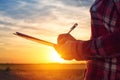 Sunset silhouette of female farmer writing notes in field