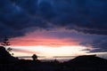 sunset with silhouette of houses and trees in the background