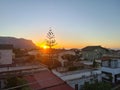 sunset with silhouette of houses and trees in the background