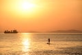 Sunset Silhouette of Man on Stand up paddle board surfing. Young man enjoying on Paddle-board on summer day. Paddling on the quiet