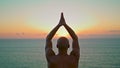 Sunset silhouette relaxing asana namaste gesture at sea. Unknown yogi practicing