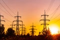 Sunset silhouettes of big electric construction. Dark shadows of high voltage electric towers. Royalty Free Stock Photo