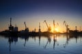 Sunset silhouettes cargo ships, cranes at sea port. Industrial loads freight at dock. Trade, transport infrastructure Royalty Free Stock Photo