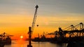 Sunset silhouettes cargo ships, cranes at sea port. Industrial loads freight at dock. Trade, transport infrastructure Royalty Free Stock Photo