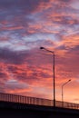 Sunset sky with brigh colorful clouds and black silhouette brige, road with lanters and fence, abstract elegant minimalistic.