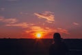 Silhouette of a girl, sky and clouds, beautiful sunset, field, pink and orange sunset