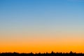 Sunset sky gradient from orange color to blue over forest horizon silhouette