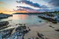 Sunset sky over beautiful beach and water bay in the greek spectacular coast line. Reflection on water, unique rocky cliffs,