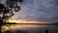 Sunset sky over lake landscape, nature background with heavy clouds and tree silhouette Royalty Free Stock Photo