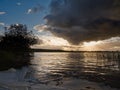 Sunset sky over a lake surface. River Corrib, Galway city, Ireland. Dark and dramatic scene. Sun flare and reflection in the water Royalty Free Stock Photo