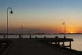 Sunset sky over the silhouettes of wooden pathway and lampposts near the sea Royalty Free Stock Photo