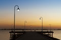 Sunset sky over the silhouettes of wooden pathway and lampposts near the sea Royalty Free Stock Photo