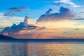 Sunset sky and sea. Seaside sunset with orange and blue clouds. Tropical sea and distant island silhouette. Royalty Free Stock Photo