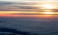 Sunset in sky view from plane flying over sea of clouds Royalty Free Stock Photo