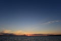 Sunset is a small bright point on the horizon the sun is infinite in space the blue of the sky and the water of the lake Royalty Free Stock Photo