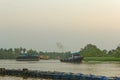 Sunset with small powerful boat pulling larger boats on freshwater river