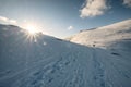 Sunset on snowy hill with mountaineers and footprint at mount Ryten