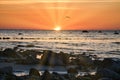 Sunset, stone beach with small and large rocks in front of the illuminated sea Royalty Free Stock Photo