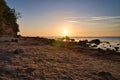 Sunset, stone beach with small and large rocks in front of the illuminated sea Royalty Free Stock Photo