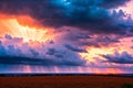 Sunset stormy sky with heavy dark blue rain clouds and bright rays of the sun. Sun rays pass through the