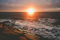 Sunset with sun flare over sea and rocks Royalty Free Stock Photo