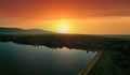 Sunset sun illuminates fields, silhouettes of Balkan mountains and lake. Panorama, top view Royalty Free Stock Photo