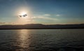 Sunset with sun partially obscured by clouds over lake and distant mountains. Royalty Free Stock Photo