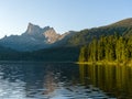 Sunset sun rays illuminate the cedars on the shores of a forest lake. View of the Star peak