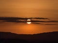 Sunset with sun shining through dark clouds above hills on horizon with orange colored sky viewed from Koblenz, Germany. Royalty Free Stock Photo