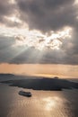 Sunset with sunbeams over Volcano with boat on Santorini island in Greece