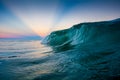 Sunset with sunrays behind a wave breaking at Campeche beach in Florianopolis Brazil Royalty Free Stock Photo